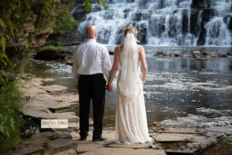 Just married couple enjoying the serenity of a cascading waterfall in the background.