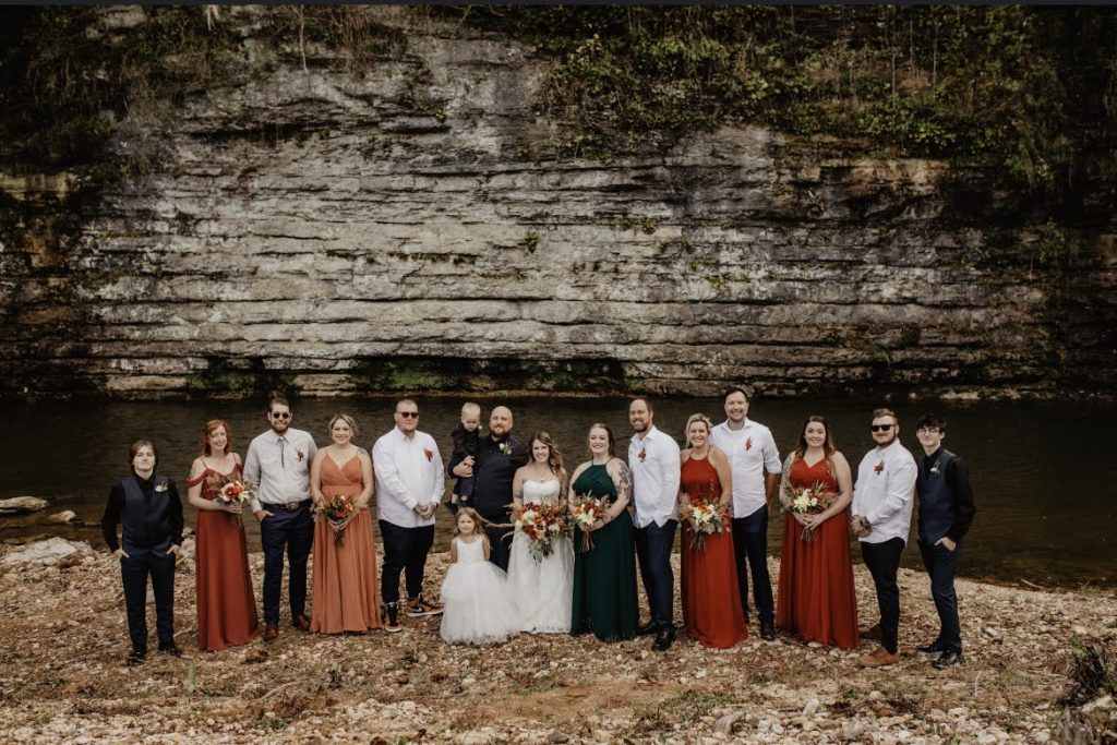 Elegance meets nature as the bridal party graces the scene against a cliff wall.